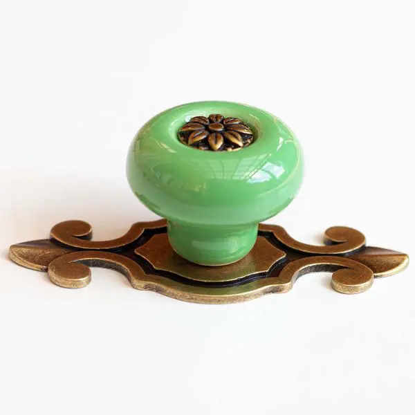 Buton de mobilă din ceramică verde cu plăcuță decorativă, ideal pentru sertare, dulapuri și noptiere în stil vintage.