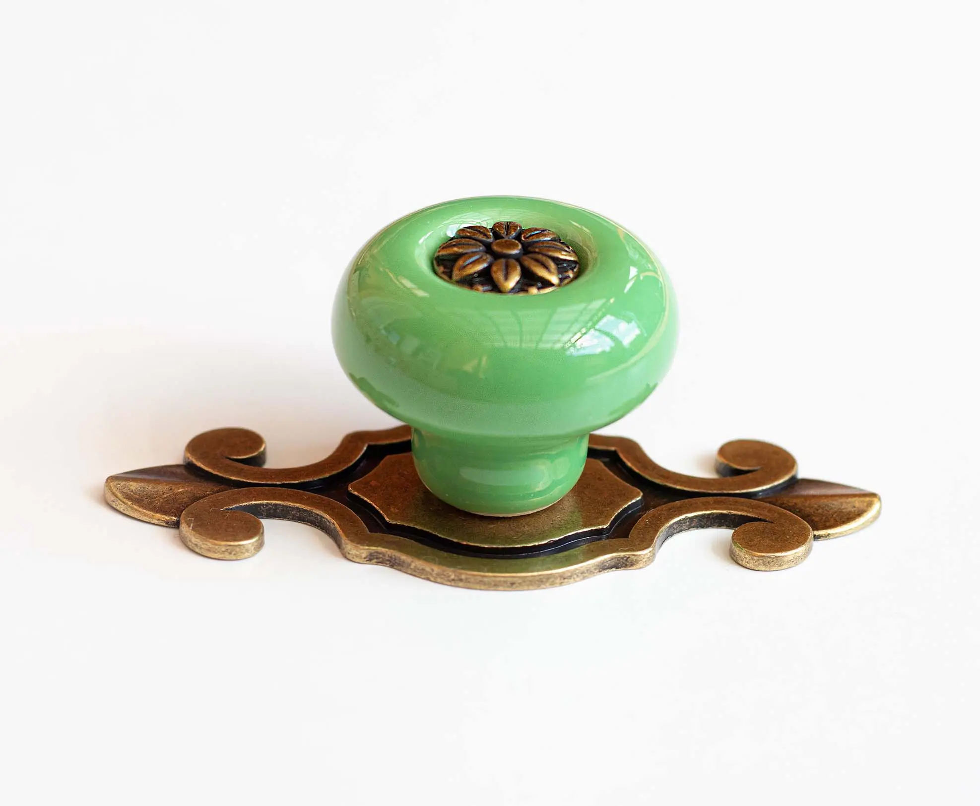 Buton de mobilă din ceramică verde cu plăcuță decorativă, ideal pentru sertare, dulapuri și noptiere în stil vintage.